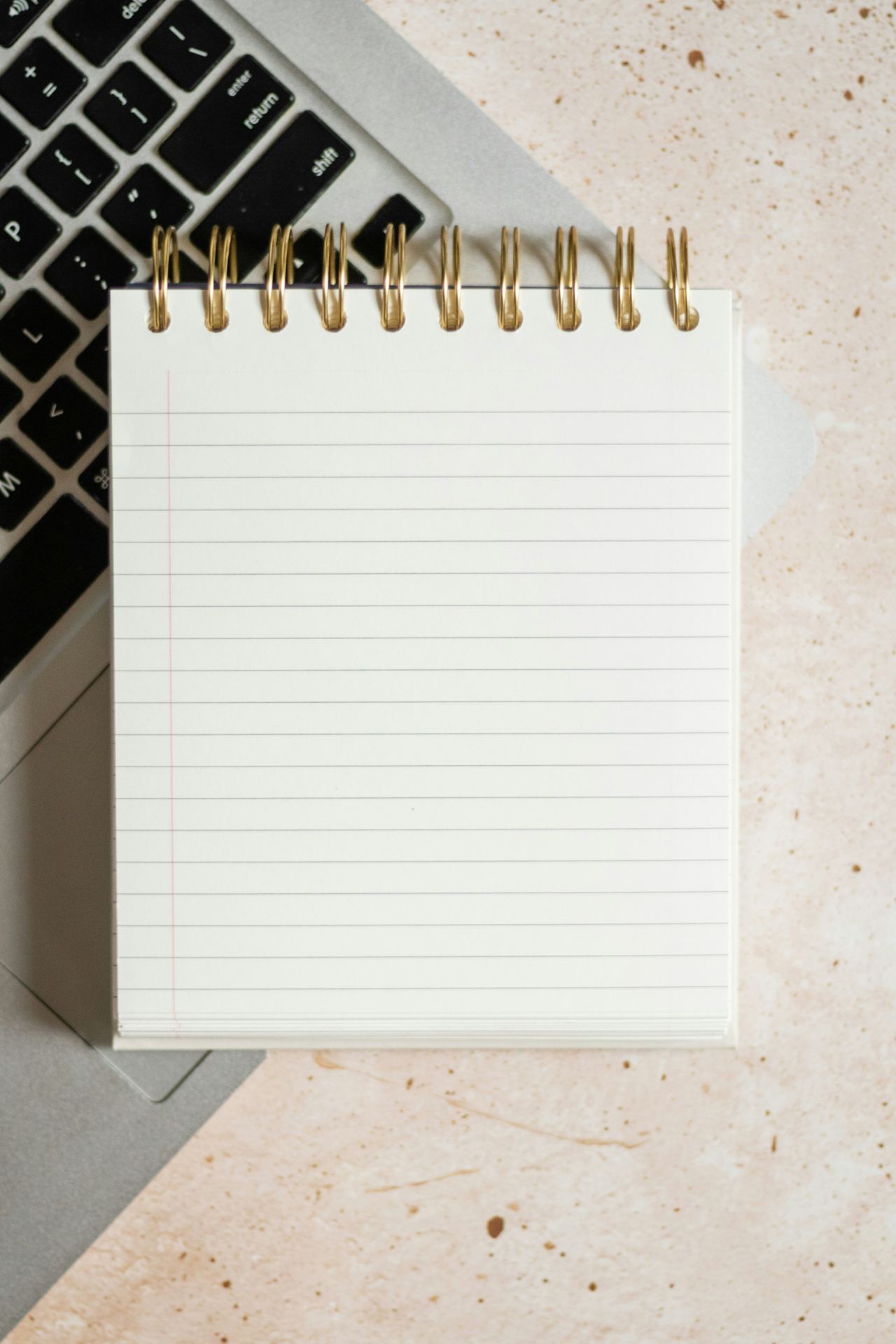 Buku catatan dan laptop di atas meja kerja, melambangkan kerja editorial